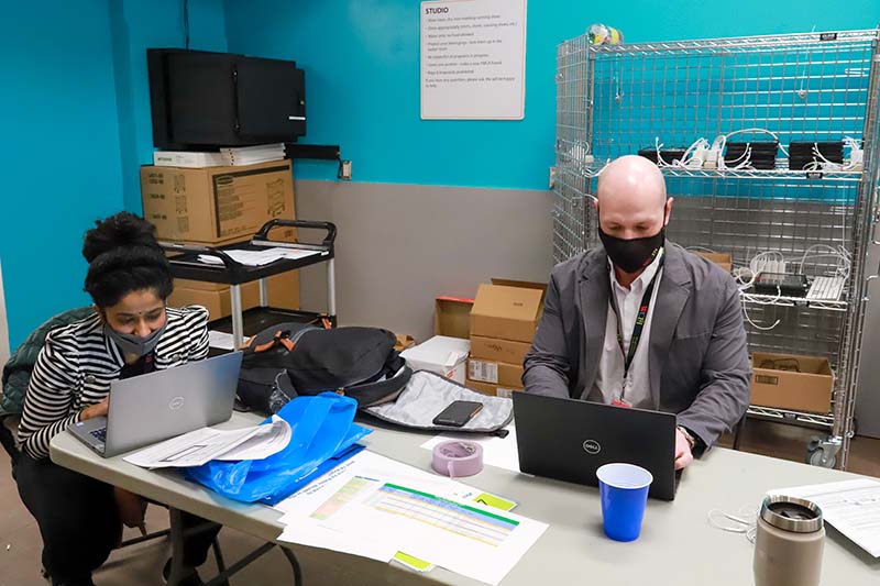 Two staff members work on laptops at a clinic