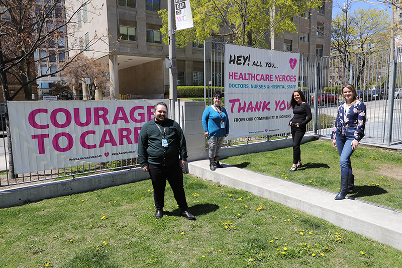 A team of social works are distanced on the lawn of the hospital