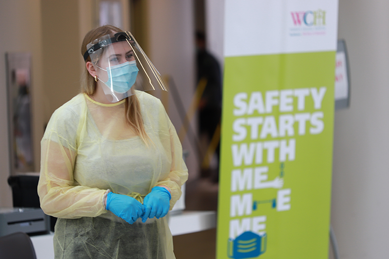 A woman in full PPE stands in the hosptial lobby